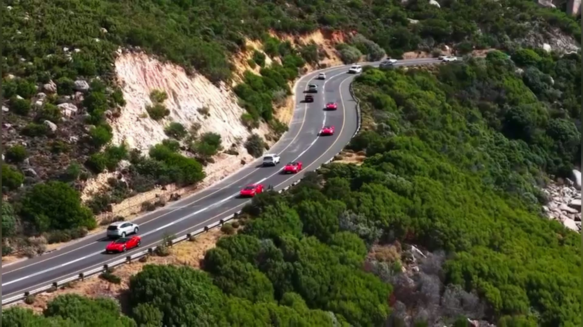 The Ferrari convoy on a coastal mountain road