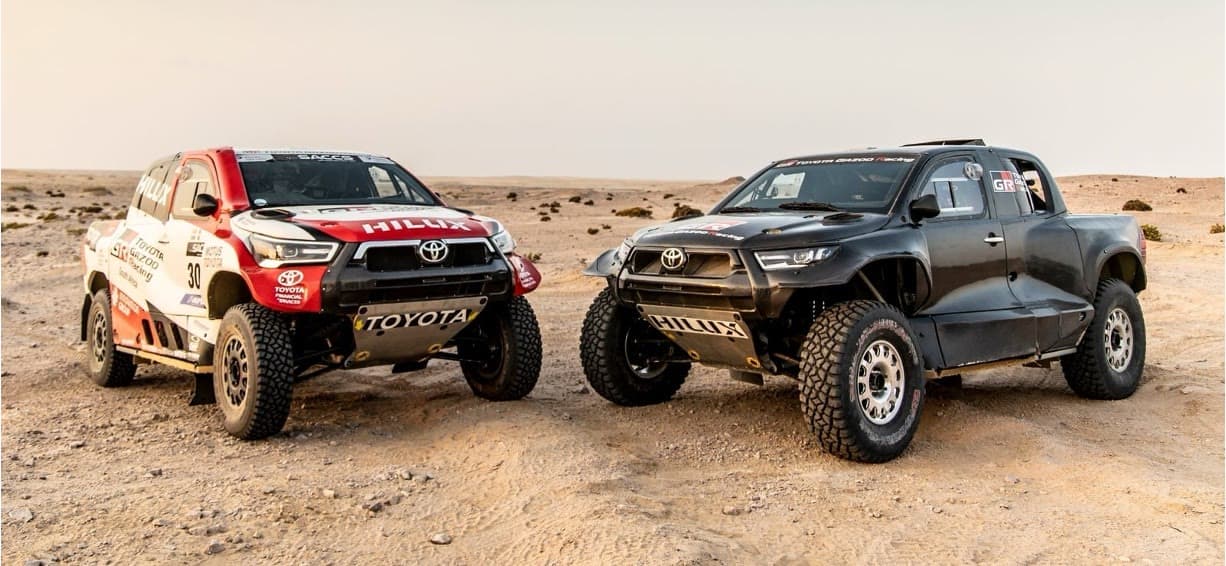 Two Toyota Gazoo Racing Hilux rally cars in the desert