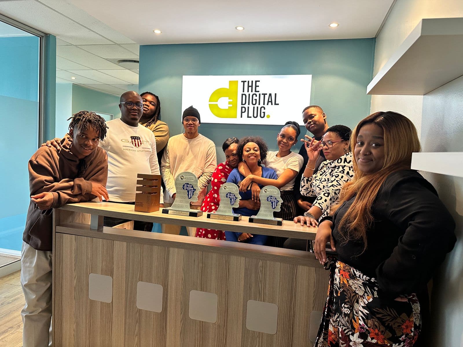 The Digital Plug team together at their Bryanston studio, with their industry award trophies on the desk.